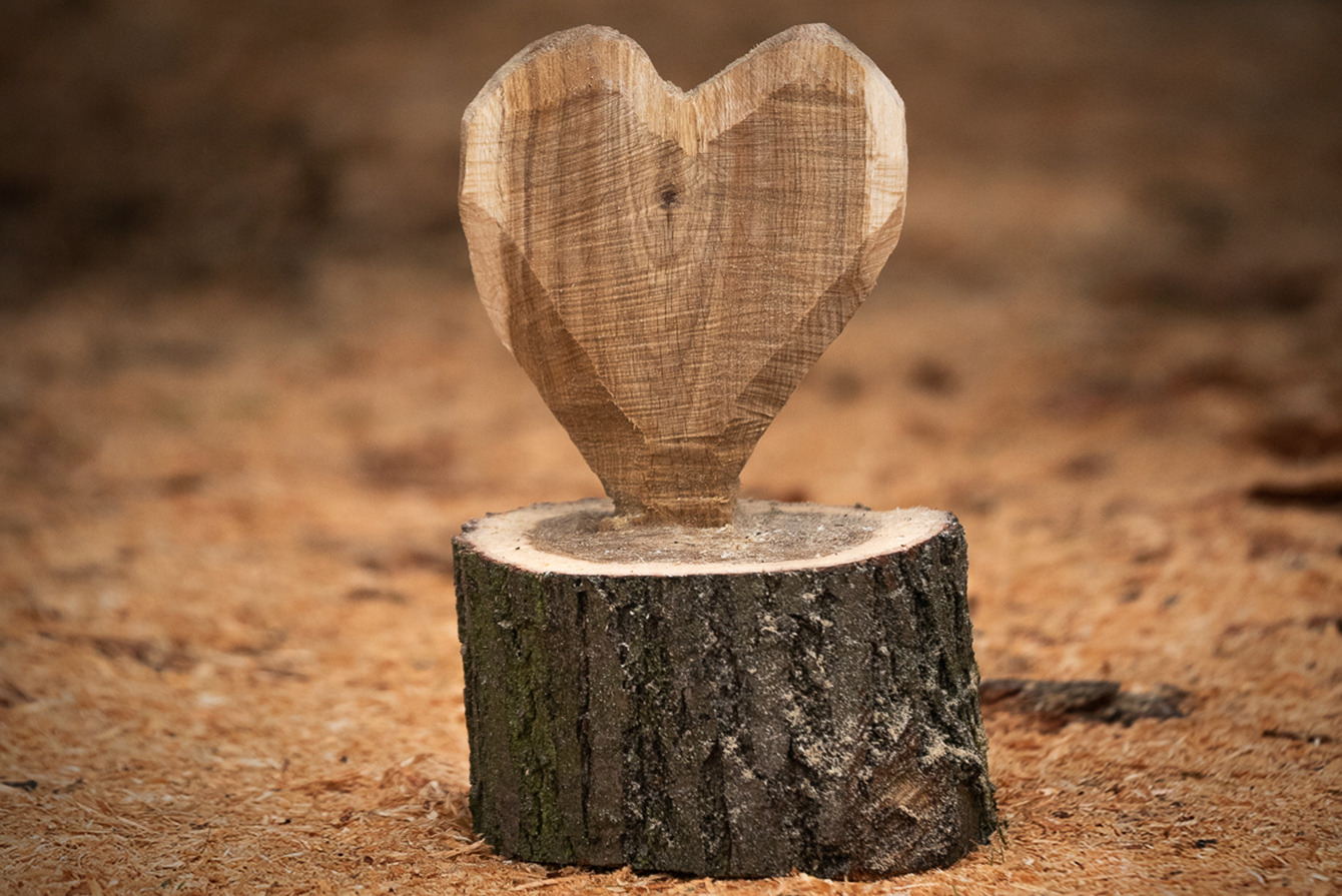 Samodzielnie wykonane drewniane serce stoi na podłodze między wiórami